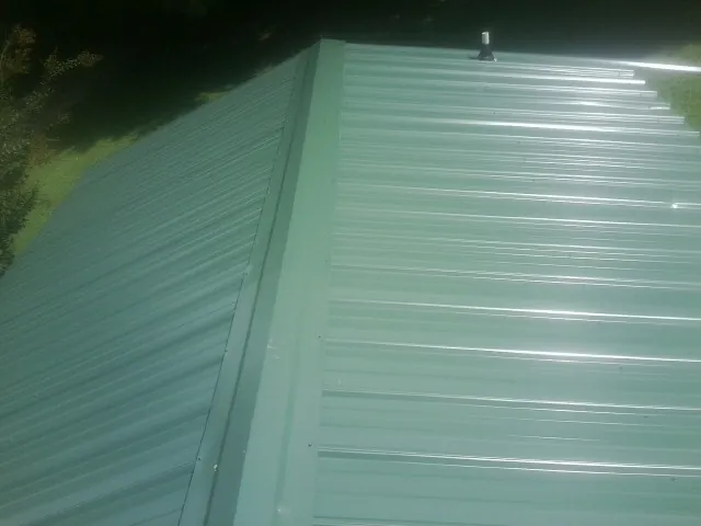 New green metal panels meeting at the ridge of a roof — Flat Roof Repair work by our crew in Silver Lake
